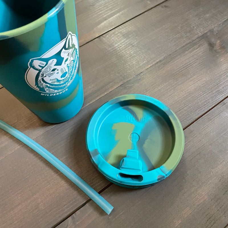 A teal and green camo-patterned tumbler adorned with a logo depicting a mountain scene and wolf&
